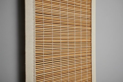 Close-up of hand-woven natural bamboo reed texture with subtle color variation and decorative edge banding