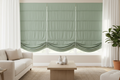 Hobbled roman shades in sage green with cascading waterfall folds in a living room