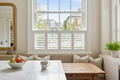 Café-style plantation shutters in soft white covering the bottom half of a kitchen window