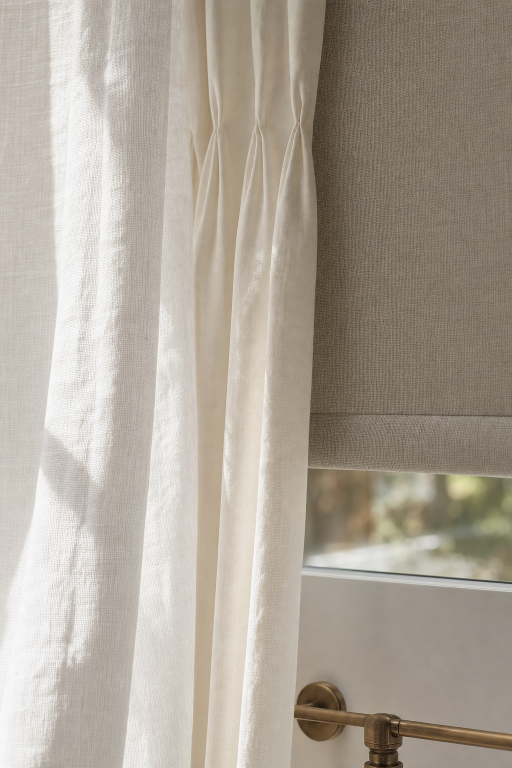 Detail of three layered window-treatment fabrics overlapping near a sunlit window